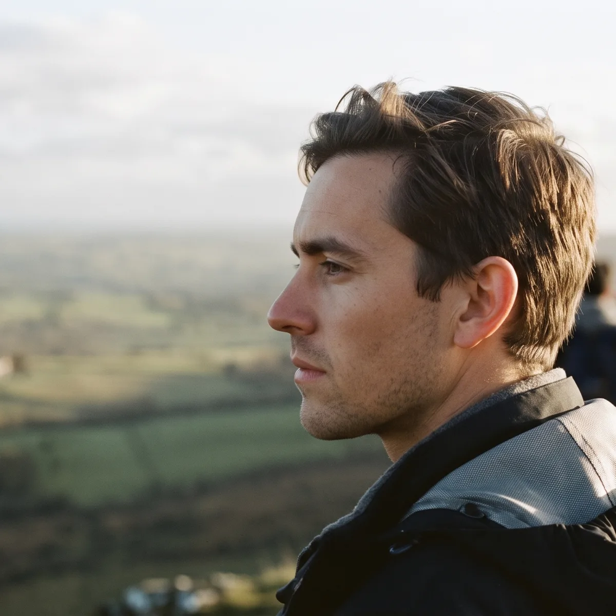 A man in profile looking out over rolling farmland