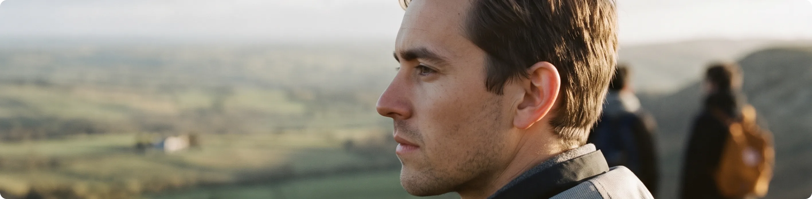 A man in profile looking out over rolling farmland